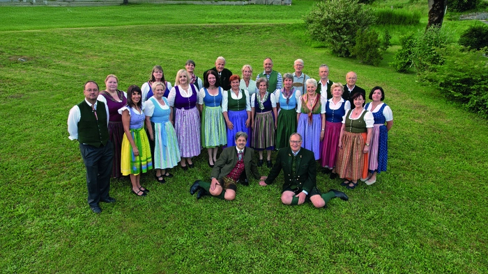 Eine Gruppe in Tracht posiert auf einer Wiese für den Fotografen