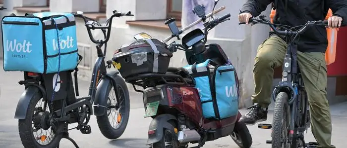 Ein E-Fatbike, ein E-Moped und ein E-Bike stehen, beladen mit blauen Essenszustellboxen, nebeneinander