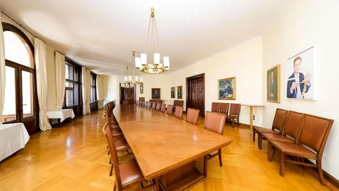 Riesiger Tisch mit zahlreichen, ledergepolsterten Stühlen; an der Wand hängen die Bilder der früheren Bürgermeister