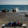 Ein Migrant schläft auf der ostägaischen Insel Lesbos auf einer steinernen Bank am Meer 