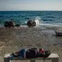Ein Migrant schläft auf der ostägaischen Insel Lesbos auf einer steinernen Bank am Meer 