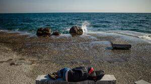 Ein Migrant schläft auf der ostägaischen Insel Lesbos auf einer steinernen Bank am Meer 