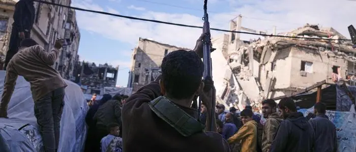 A Palestinian man fires in the air during the funeral of Hamas' Al-Qassam Brigades operatives, killed in an Israeli strike Saturday, in Gaza City, Sunday, Dec. 14, 2025. (AP Photo/Jehad Alshrafi)