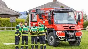 Vier Männer stehen neben einem Feuerwehrauto, vor ihnen steigt eine Drohne auf