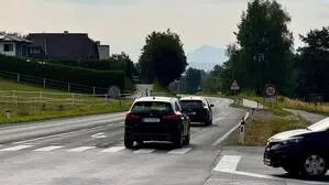 Blick auf eine Kreuzung, zwei Autos fahren auf der Vorrangstraße, ein Auto steht als Abbieger da