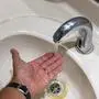 Das Bild zeigt ein Waschbecken. Unter den laufenden Wasserhahn wird eine Hand gehalten
