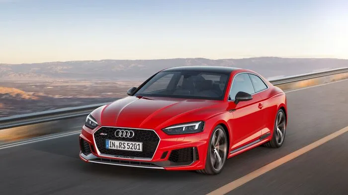 Das RS 5 Coupé trägt massive Lufteinlässe mit RS-typischer Wabenstruktur zur Schau. Der Singleframe-Kühlergrill ist deutlich breiter und flacher als beim Basismodell. Die optionalen Matrix LED-Scheinwerfer sind durch abgedunkelte Blenden differenziert. An den Flanken betonen Quattro-Blister die kräftigen Wölbungen über den um 15 Millimeter verbreiterten Radhäusern.