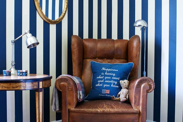 Streifenlook aus Stockholm: Krstina und Tommy Lindhe haben für ein Gästezimmer in ihrem Haus in Stockholm eine Blockstreifentapete gewählt, die den Raum optisch vergrößert. Ein alter Ledersessel und ein gestreifter Läufer tragen zur behaglichen Atmosphäre bei.