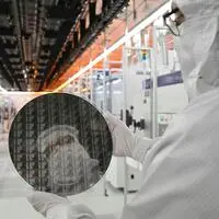 Ein Infineon-Mitarbeiter mit einem Galliumnitrid-Wafer im vollautomatisierten Reinraum der Chipfabrik in Villach