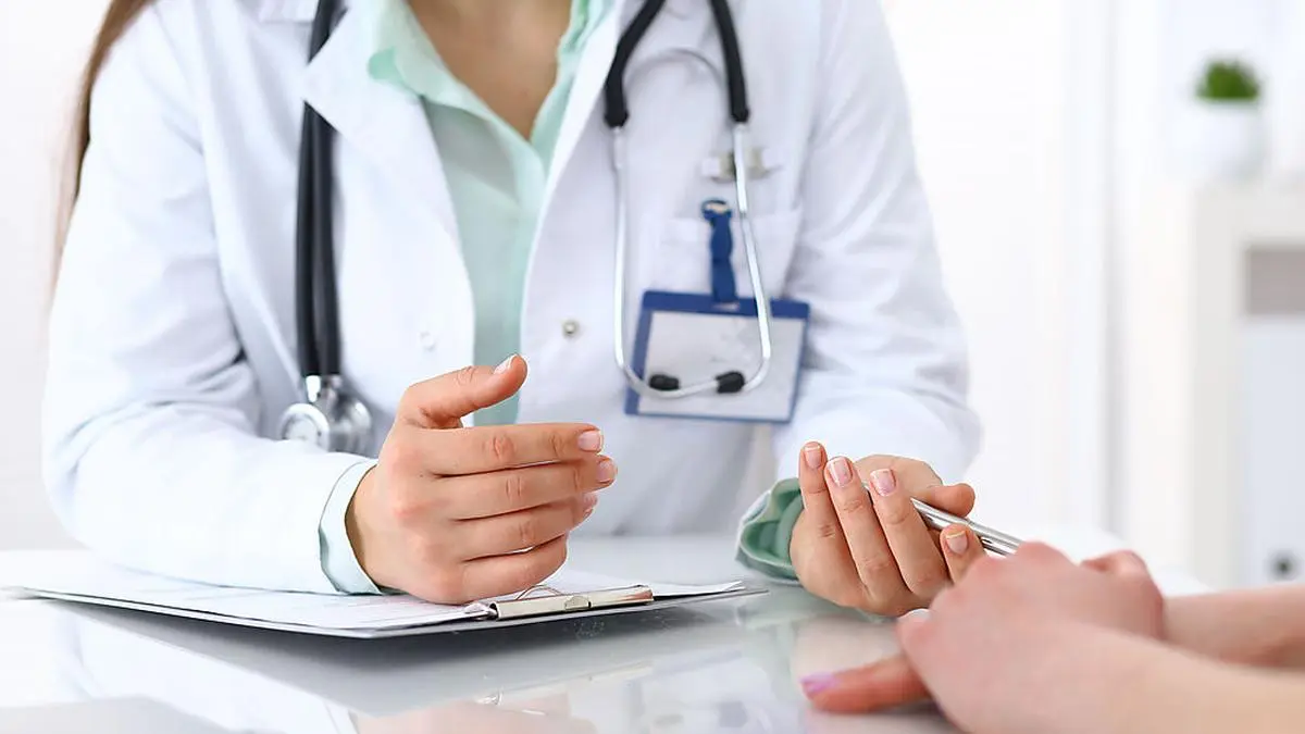 Doctor and patient talking while sitting at the desk in hospital office, closeup of human hands. Medicine and health care concept.