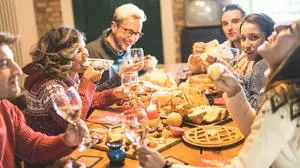 Front view of friends group tasting christmas sweets food and having fun at home drinking champagne sparkling wine - Winter holidays concept with people enjoying time eating together - Warm filter
