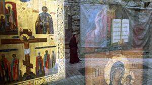 Eine christliche  Pilgerin mit einem Holzkreuz in der Hand spiegelt sich in der Auslage eines Ikonen-Geschäfts in Jerusalem 