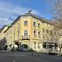 Außenansicht auf ein großes Eckgebäude mit gelber Fassade
