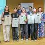 Einige Schülerinnen und Schüler lächeln in die Kamera und halten eine Auszeichnung in ihren Händen.