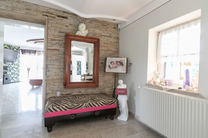 Der „extravagante Landhausstil“, wie ihn der Hausherr nennt, wurde auch im Zubau beibehalten. Überall finden sich individuelle Einzelstücke wie die Sitzbank im Eingangsbereich, die Elisabeth Fuchs mit einem Stoff nach dem Lieblingsmuster auf ihrer Handtasche bespannen ließ.
