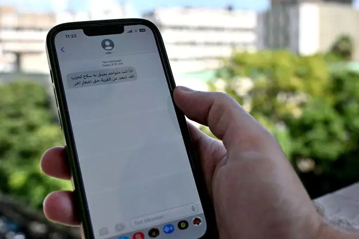 A Lebanese man checks a message received on his mobile phone in Beirut on September 23, 2024, calling people to evacuate the areas where Hezbollah hides its weapons. Israel's military pounded Hezbollah targets in south and east Lebanon on September 23 and said more strikes were coming, warning Lebanese to stay out of harm's way despite international calls for restraint. (Photo by JOSEPH EID / AFP)