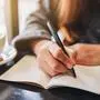 Closeup image of a woman writing on a blank notebook on the table 