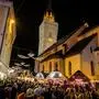 Viele Menschen auf einem Platz mit weihnachtlich beleuchteten Hütten, im Hintergrund ein beleuchteter Kirchturm | Gäste des Villacher Advents müssen für das Aufsuchen einer Toilette das Gelände verlassen oder Lokale aufsuchen