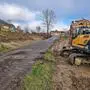 Der Erdhaufen beim Gerinne wird umgesetzt, damit es dort keinen Eintrag geben kann. Ein Bagger steht schon bereit