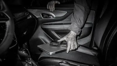 Ein Mann stiehlt ein Notebook aus einem Auto