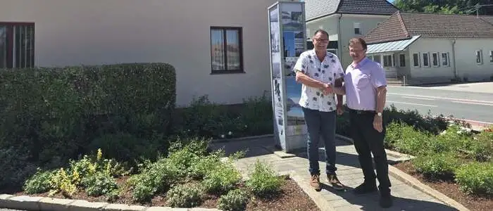 Zwei Männer schütteln sich die Hände vor dem Gemeindeamt