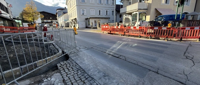 Ein grau übermalter Zebrastreifen auf einer Straße in Lienz. Im Vorder- und Hintergrund sind zwei Baustellen