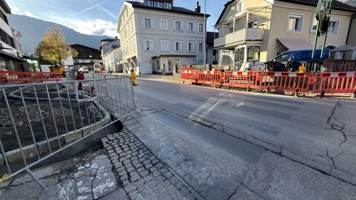 Ein grau übermalter Zebrastreifen auf einer Straße in Lienz. Im Vorder- und Hintergrund sind zwei Baustellen