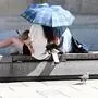 Themenfoto Hitze: Eine Familie sucht bei hochsommerlichen Temperaturen Schutz unter einem Regenschirm