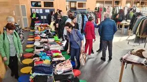 Man sieht Tische und Ständer mit Kleidung, die Menschen sich ansehen