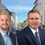 Zwei Männer im Vordergrund, im Hintergrund ist die St. Veiter Innenstadt zu sehen.
