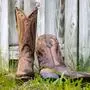 Classic Western Cowboy Boots Outdoors. Brown leather boot with stitching near wooden fence