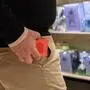 Ein Mann steckt eine Parfumverpackung in die Hosentasche