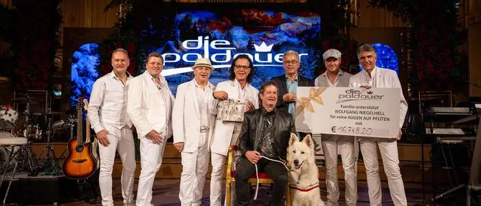 „Die Paldauer“ übergaben gemeinsam mit Ideengeber Achim Sonnendorfer (3. v. r.) den Spendenscheck an den blinden Panflötisten Wolfgang Niegelhell und seinen Hund Amando (vorne sitzend)
