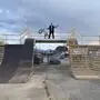 BMX-Sportler Kevin Böck steht mit seinem BMX-Rad in der Hand auf einer hohen Rampe aus Holz, die er selbst gebaut hat