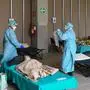 Hospital employees wearing protection mask and gear tend to patients lying in bed at a temporary emergency structure set up outside the accident and emergency department, where any new arrivals presenting suspect new coronavirus symptoms will be tested, at the Brescia hospital, Lombardy, on March 13, 2020. (Photo by Miguel MEDINA / AFP)