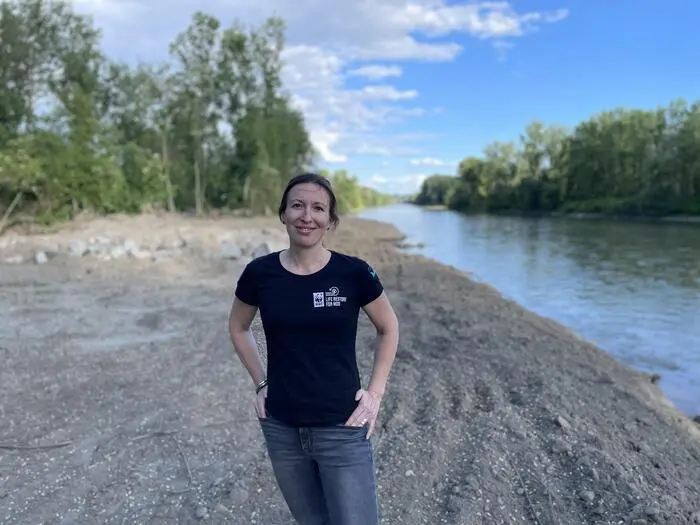 Lisa Wolf steht am Ufer der Mur, hinter ihr eine Erdfläche, die von den Baggern bereits bearbeitet worden ist