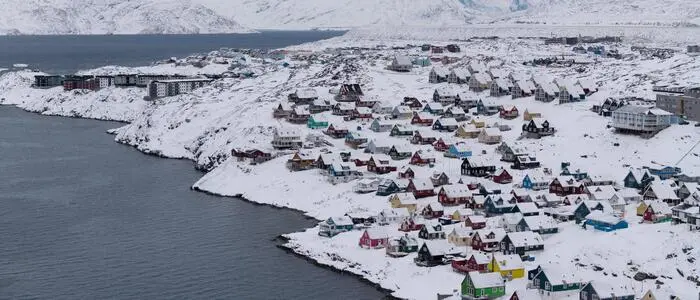 Schneebedeckte Häuser auf Grönland direkt am Wasser