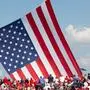 TOPSHOT - Trump supporters cheers as the American flag is untangled before former US President and Republican presidential candidate Donald Trump speaks during a campaign event at Butler Farm Show Inc. in Butler, Pennsylvania, July 13, 2024. Donald Trump was hit in the ear in an apparent assassination attempt by a gunman at a campaign rally on Saturday, in a chaotic and shocking incident that will fuel fears of instability ahead of the 2024 US presidential election. (Photo by Rebecca DROKE / AFP)