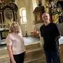 Eine blonde Frau und ein dünner Mann stehen in einer Kirche