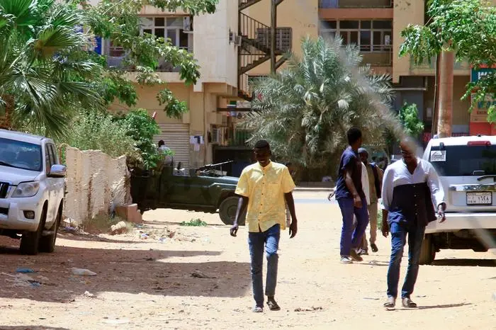 People walk past a military vehicle in Khartoum on April 15, 2023, amid reported clashes in the city. - Sudan's paramilitaries said they were in control of several key sites following fighting with the regular army on April 15, including the presidential palace in central Khartoum. (Photo by AFP)