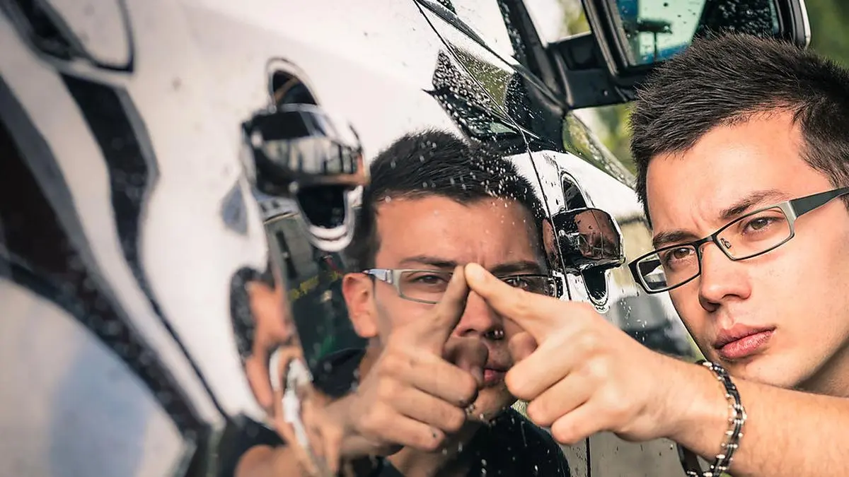 Young man with glasses inspecting a luxury car before a second hand trade