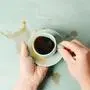 Zitternde Hände, die Kaffee aus einer Tasse verschütten
