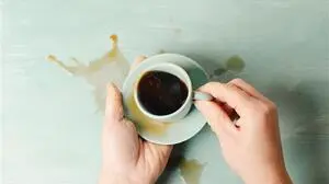 Zitternde Hände, die Kaffee aus einer Tasse verschütten