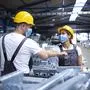 Workers greeting each other with elbow bump due to global corona virus pandemic and danger of infection. Employees standing in factory wearing protection mask.