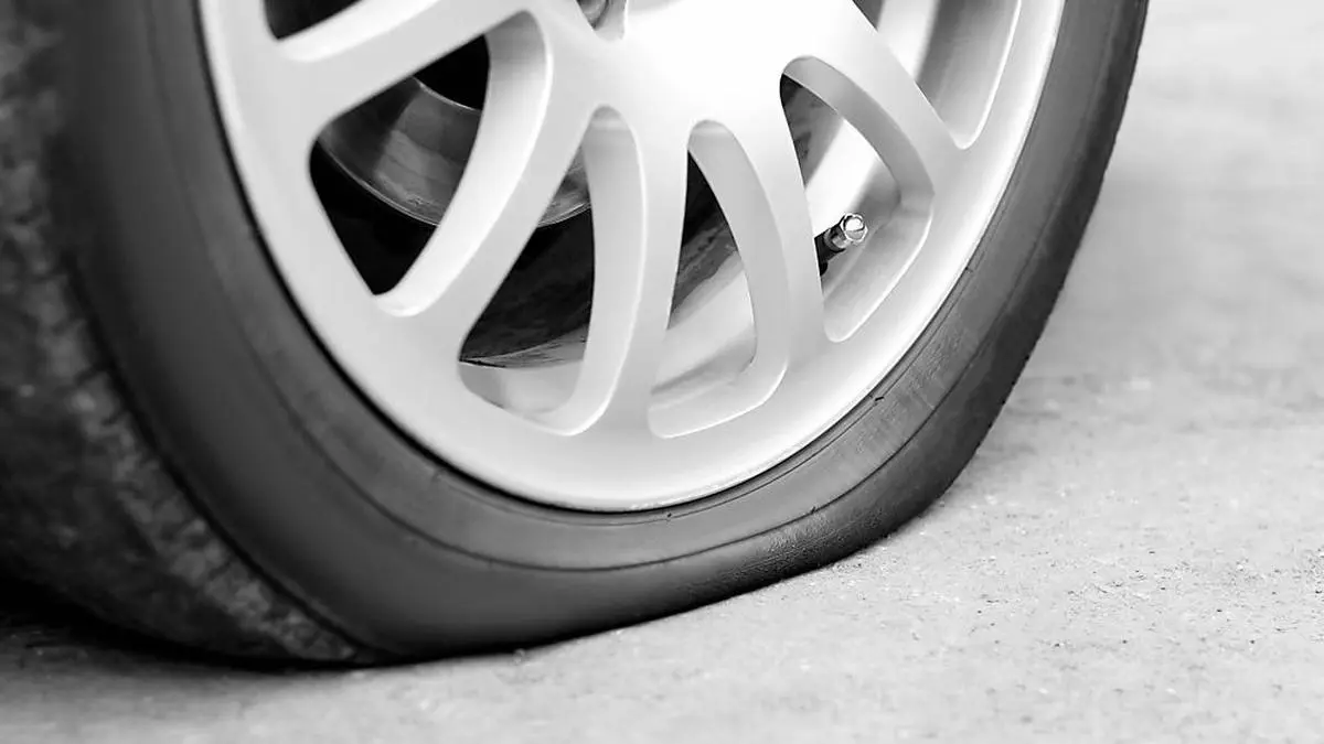 Flat tire on the car. Silver forged wheel. Close up.