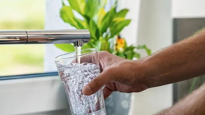 Eine Hand hält ein Glas Wasser