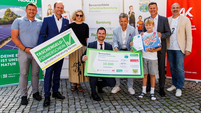 Finanzbildung von klein auf, um gemeinsam Großes zu erreichen: Das Team der Schuldnerberatung Kärnten mit dem Land Kärnten und Partnern bei der Übergabe an den 10.000sten Teilnehmer im Zuge des Taschengeld-Führerscheins. Finanzwissen stärkt Kinder – heute für morgen