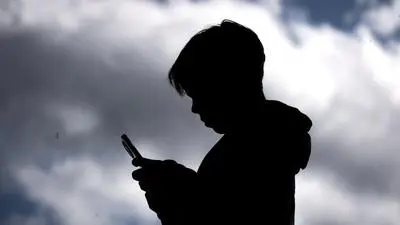 This photo taken on October 24, 2025 shows a 14-year-old boy posing at his home near Gosford as he looks at social media on his mobile phone. Tech giants Meta and TikTok said on October 28 they will obey Australia's under-16 social media ban but warned the landmark laws could prove difficult to enforce. Australia will from December 10 force social media platforms such as Facebook, Instagram and TikTok to remove users under the age of 16. (Photo by David GRAY / AFP)