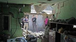 OSZE-Beobachter dokumentieren in einem Wohnviertel der ostukrainischen Stadt Dokutschajewsk Kriegsschäden  