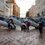 Residents walk past piled up cars following deadly floods in Sedavi, south of Valencia, eastern Spain, on October 30, 2024. Floods triggered by torrential rains in Spain's eastern Valencia region has left at least 70 people dead, rescue services said on October 30. (Photo by Manaure QUINTERO / AFP)